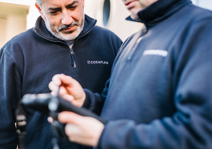 Dos técnicos de Cosaplag uniformados revisando datos en un dispositivo digital durante una inspección de seguridad alimentaria, garantizando el cumplimiento de la normativa vigente.